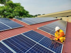 A solar technician performs maintenance on rooftop solar panels enhancing energy efficiency. Stock Photo
