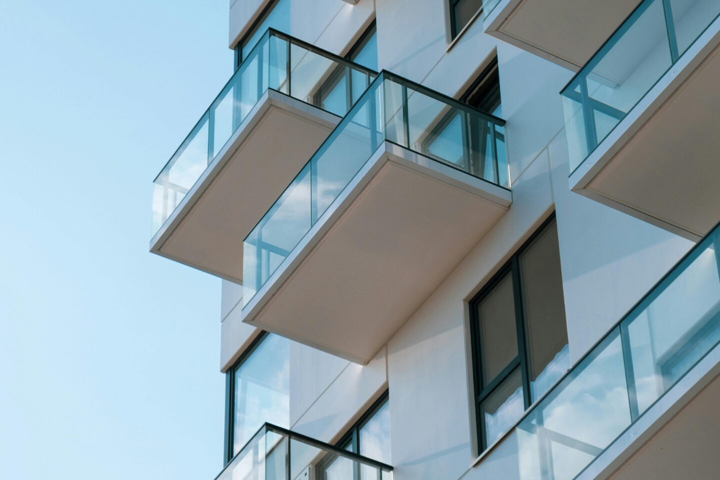 Stylish residential building featuring glass balconies against a clear blue sky. Stock Photo