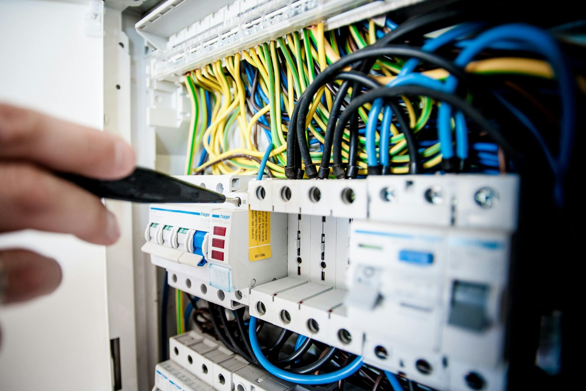 Free Hand of electrician working on a circuit breaker panel with colorful wires, ensuring safe electrical connections. Stock Photo